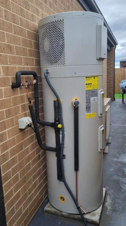 Heat pump hot water system installed against a brick wall